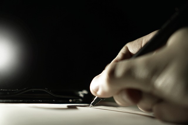 A person signing a document with a pen