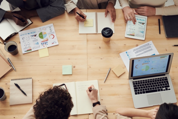 Table with a number of people around it with paper and a laptop